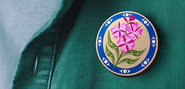 Close-up of BCAA Fireweed pin badge worn on green shirt