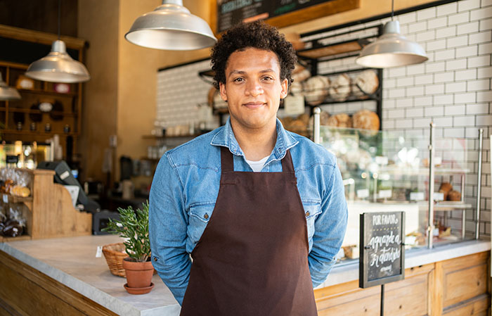 Man in apron standing in front of a cafe countertop