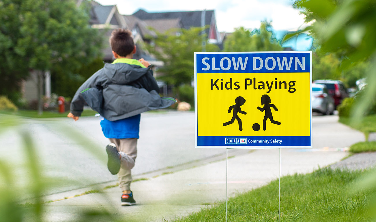 boy runs by slow down kids playing lawn sign