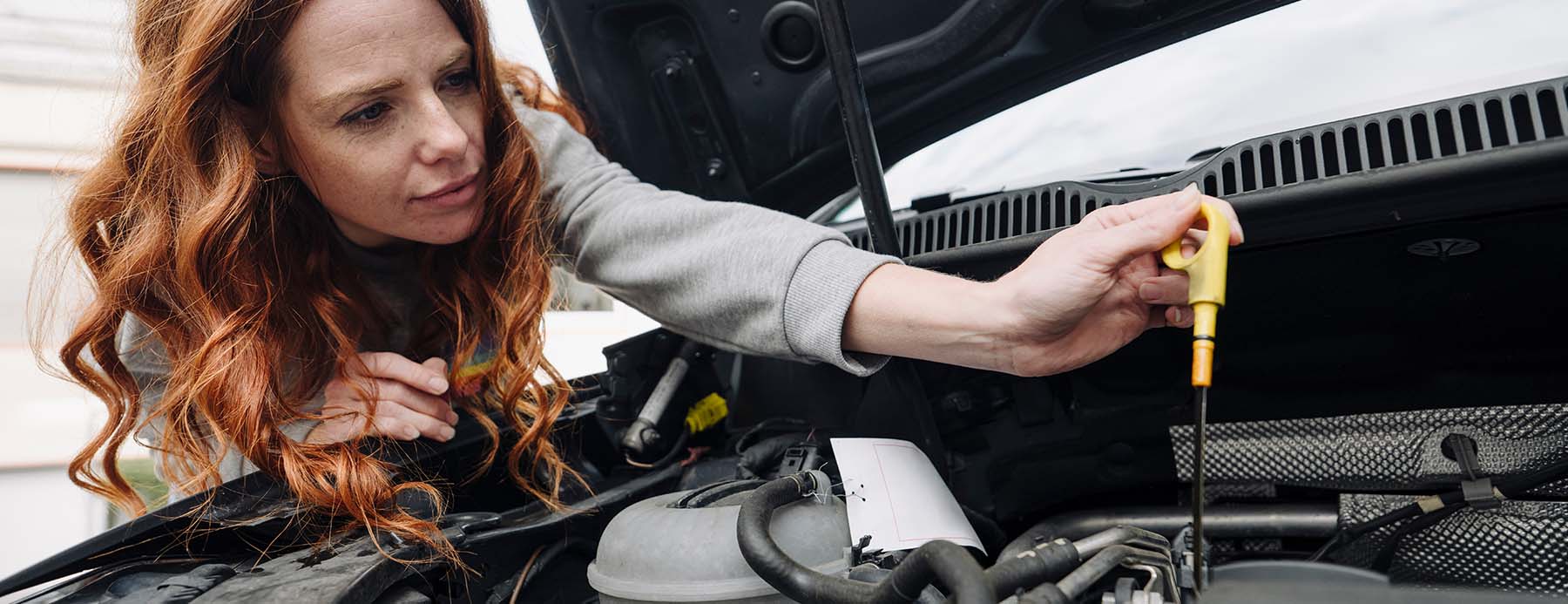 woman checking motor oil of her car