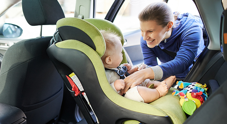 a mother secures her child in a car seat