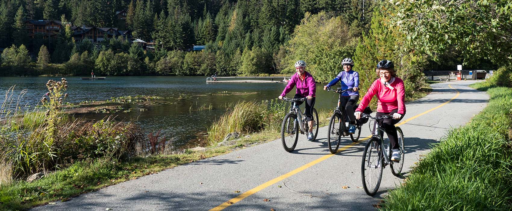 Three adults cycling around a lake