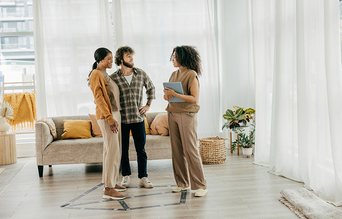 Couple and real estate agent standing in bright condo living room