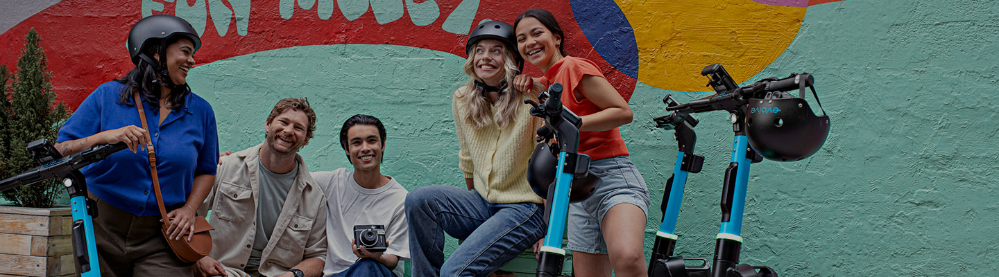 Group of teens enjoying and posing with evolve e-bikes and e-scooters