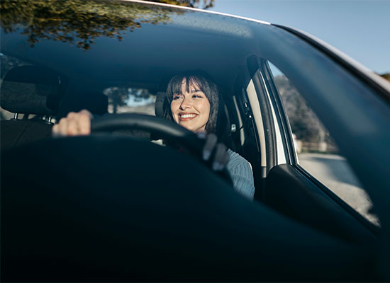 Happy woman is driving a car on a sunny day