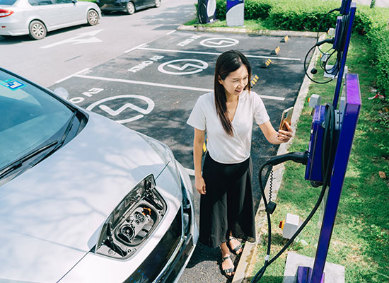 Woman is charging her EV car and taking a photo