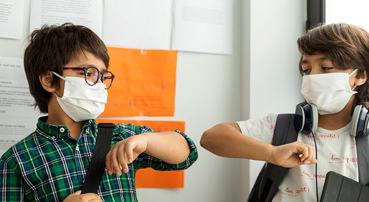 boys wearing masks and bumping elbows