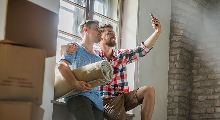 couple unpacking their belongings at their new home and taking a selfie with mobile phone