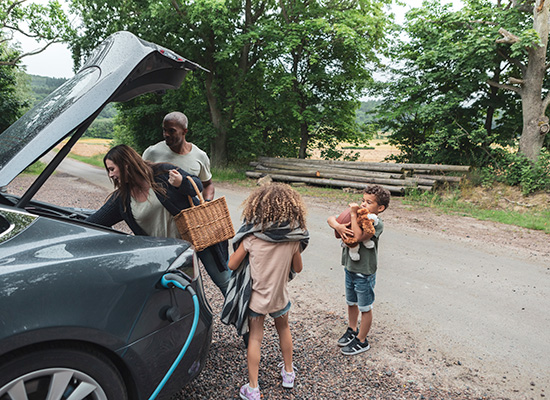 Family unloading picnic from trunk of electric vehicle