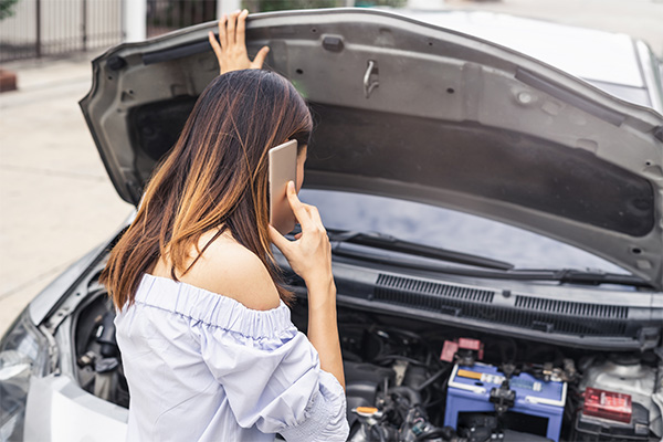 woman with broken down car calling on phone