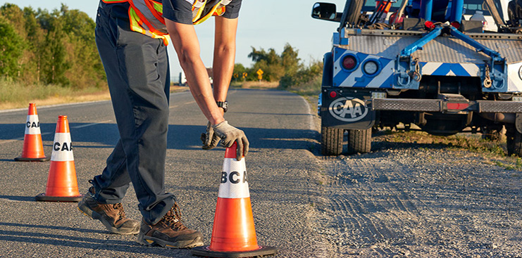 BCAA Roadside assistance laying orange cones on the road at sunset