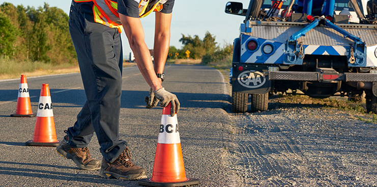 BCAA Roadside assistance laying orange cones on the road at sunset