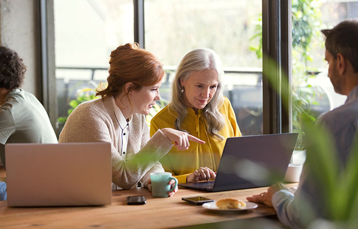 Two ladies talking at a cafe, looking at a laptop