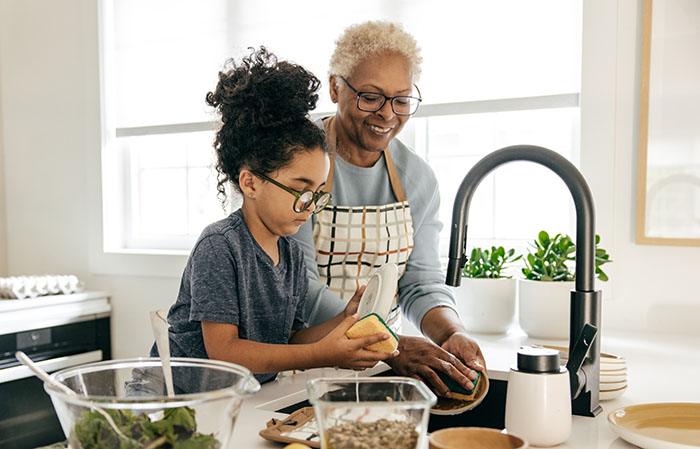 Granddaughter and grandmother washing hands in kitchen sink